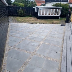 errasse med firkantede fliser, der er lagt i et moderne mønster. Den nye belægning skaber et stilrent udendørs område i Aalborg.