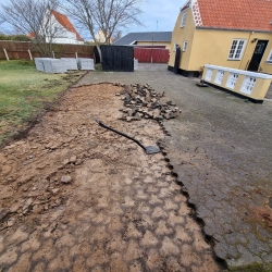 Område i Aalborg, hvor gamle fliser er ved at blive fjernet for at gøre plads til ny belægning, hvilket forbedrer gårdens udseende.