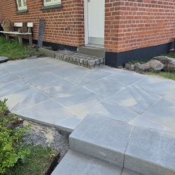 Flisebelagt gang ved husets indgang i Aalborg, skaber en pæn og funktionel forbindelse mellem hus og have.