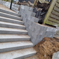 Nybygget trappe med støttevæg langs en skråning i Hjørring, hvor fliser og mursten giver en robust og sikker passage.