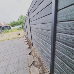 Langt hegn langs kanten af en græsplæne og terrasse i Hjørring. Hegnet giver struktur til haven og skaber et privat udendørs område.