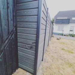 Nærbillede af et sort hegn i en have i Hjørring. Hegnet er robust og adskiller haven fra naboerne, hvilket skaber privatliv i udendørsområdet