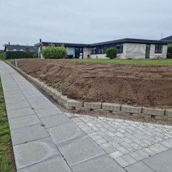 Et stort havebed, hvor jorden er klar til beplantning efter oprydning og jordbearbejdning. Bedet står klar til ny beplantning og design