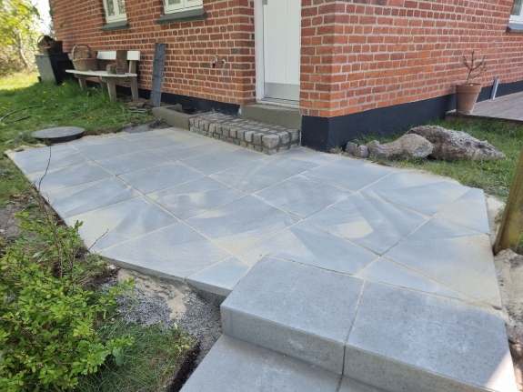 Flisebelagt gang ved husets indgang i Aalborg, skaber en pæn og funktionel forbindelse mellem hus og have.