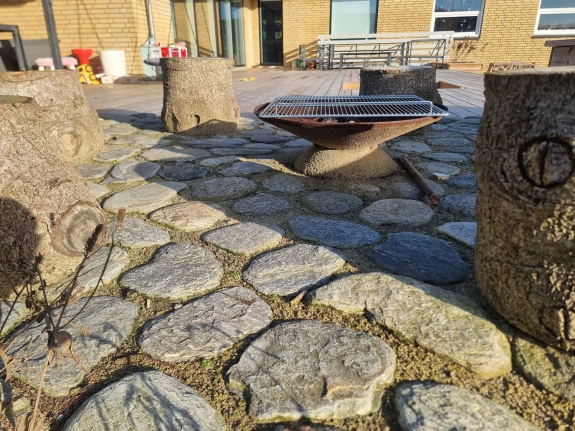 Belægning af natursten omkring en siddeplads i haven i Hjørring. Stenene skaber et hyggeligt og afslappende udemiljø.