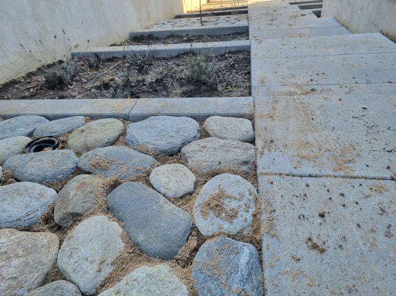 Belægning med store sten langs en havegang i Hjørring, der tilfører haven et rustikt og naturligt udseende.