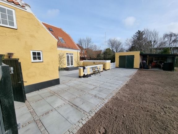 Nybelagt terrasse ved indgangen til en bolig i Aalborg. Fliserne skaber en stilfuld og holdbar belægning for udendørsarealet.