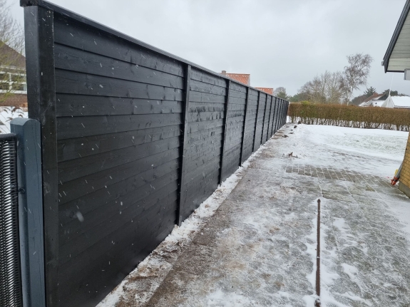 Nærbillede af et sort hegn i Aalborg med et moderne, minimalistisk design. Hegnet står langs en havegang og tilfører et stilfuldt element til udendørsområdet.